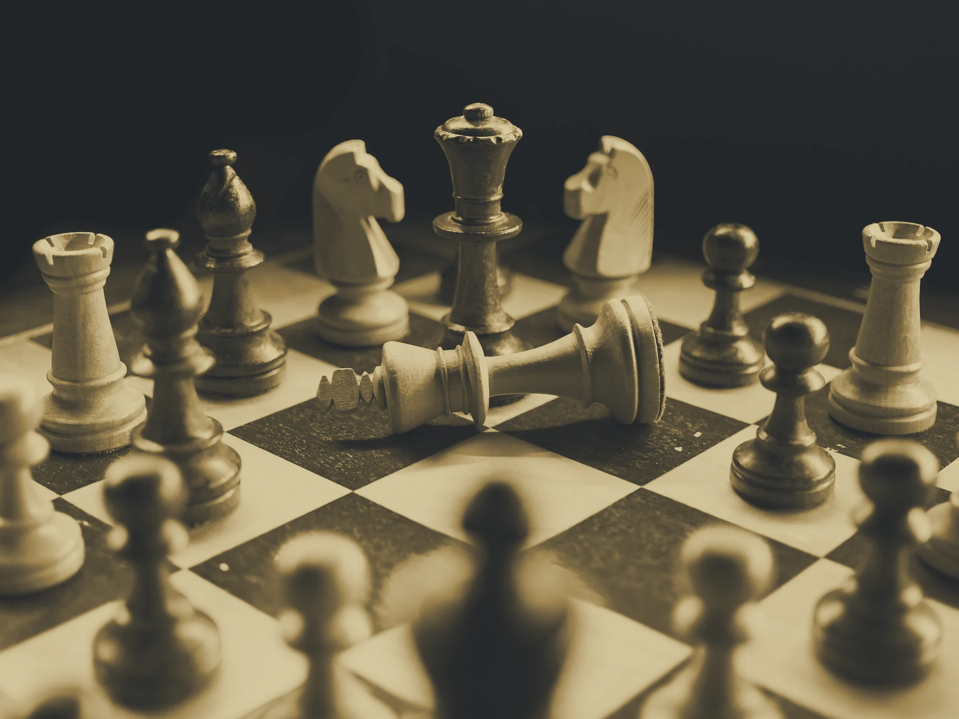 Chessboard with a toppled king among standing pieces