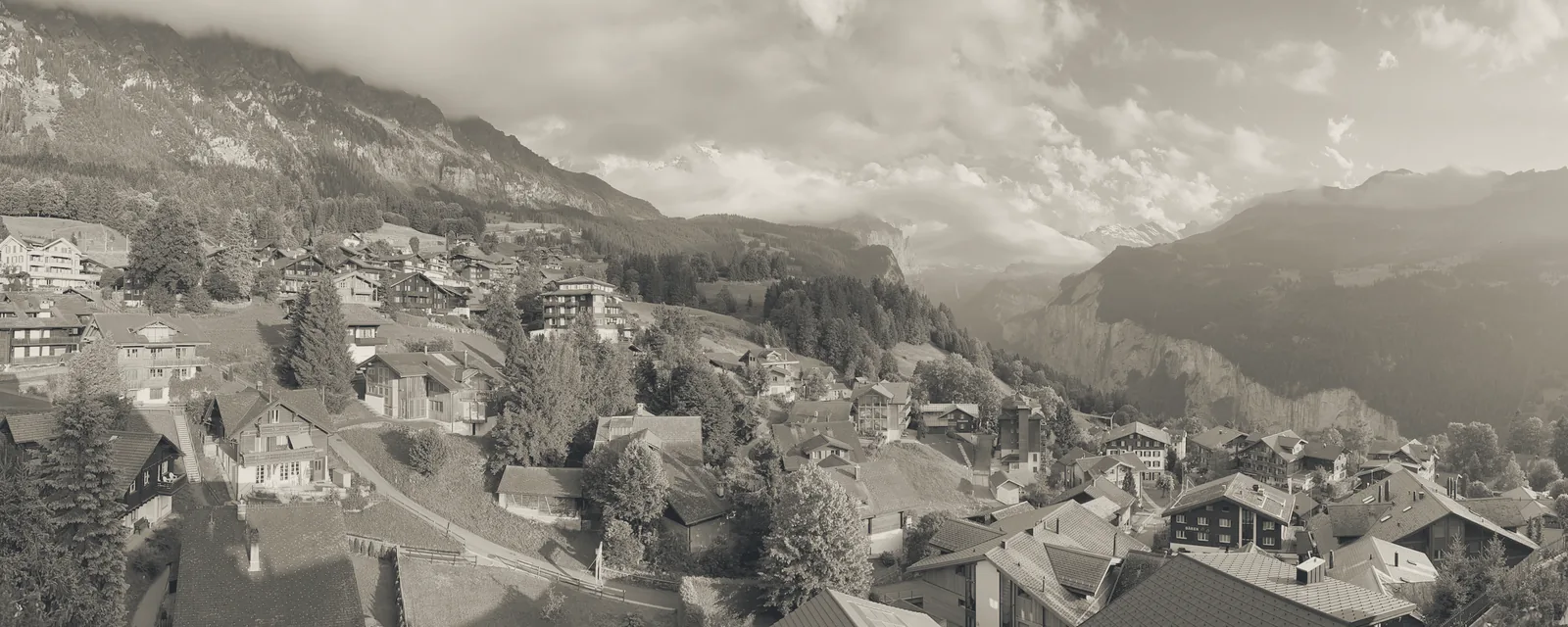 Schweizer Dorf am Hang mit Chalets vor einer Bergkulisse