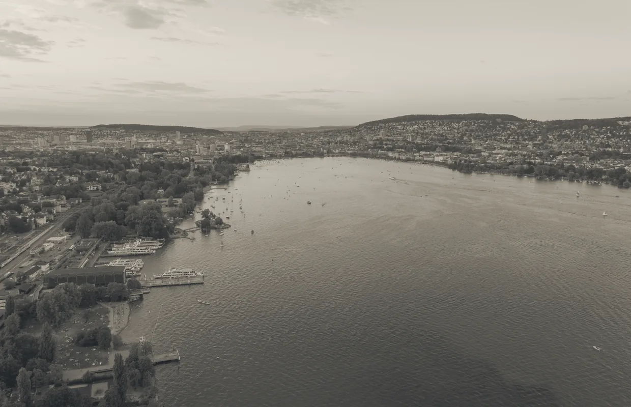 Aerial view of the lower end of Lake Zurich with boat landings, small boats and the city along the shore